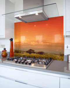 Pannello decorativo in cucina con stampa ad alta definizione di un paesaggio al tramonto, installato come schienale dietro i fornelli.